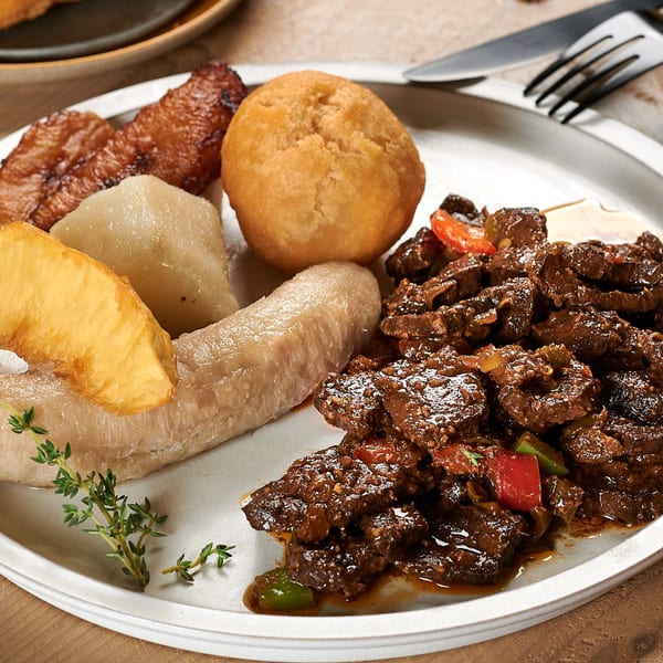 A plate of Negril Jamaican Restaurant's stewed beef, fried plantains, dumplings, and boiled bananas.